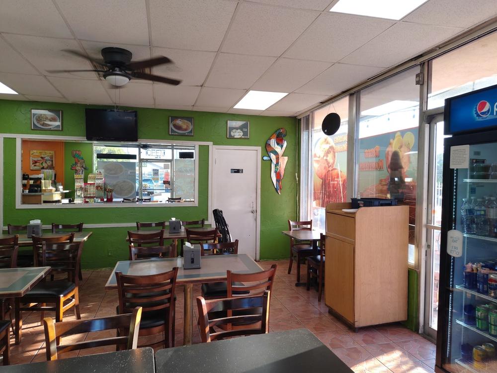 Dining room at Brito's with green walls, wood tables and a ceiling fan