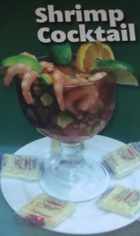 Shrimp cocktail in a tall glass with crackers